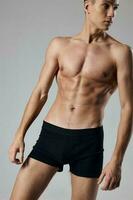 sportlich Mann im schwarz kurze Hose auf nackt Körper grau Hintergrund Muskel foto