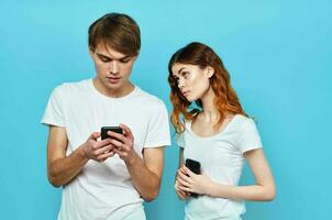 Mann und Frau Stehen Nächster zu das Telefon im Hände Kommunikation Technologie Blau Hintergrund foto