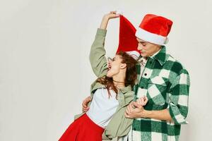 ein Mann hält ein Frau im seine Waffen ein Weihnachten Hut Urlaub Emotionen Geschenke Freundschaft grau Hintergrund foto