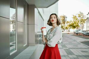 heiter ziemlich blond Tasse von heiß trinken draußen foto