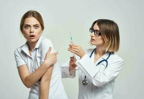 erschrocken geduldig und Krankenschwester mit ein Spritze im Hand auf ein Licht Hintergrund foto