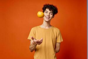 gut aussehend Mann mit lockig Haar Orangen im Hände Studio isoliert Hintergrund foto