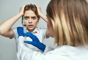 weiblich Arzt im Blau Handschuhe Injektion Spritze Kommunikation geduldig foto