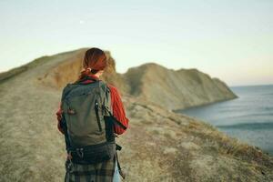 Frau Wanderer mit ein Rucksack auf ihr zurück Gehen im das Berge Abenteuer frisch Luft foto