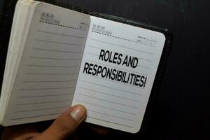 Rollen und Verantwortlichkeiten schreiben auf Notizbuch isoliert auf schwarz Hintergrund foto