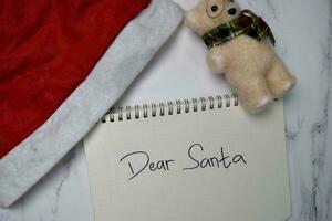 sehr geehrter Santa schreiben auf ein Buch isoliert hölzern Tisch. foto