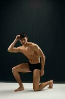 Restwert muskulös Körper Mann im dunkel Höschen kniet Studio Lebensstil foto