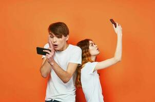 ein Mann und ein Frau im Weiß T-Shirts halten Telefone Kommunikation Unterhaltung foto