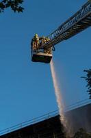 Feuerwehrleute klettern Leiter gegen Gebäude foto