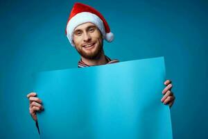 gut aussehend Mann im ein Santa Hut halten ein Banner Urlaub Studio posieren foto