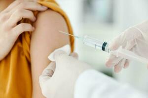 Arzt spritzen Impfstoff in Schulter von geduldig tragen medizinisch Maske im Krankenhaus Epidemie foto