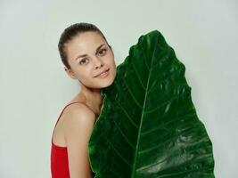 ziemlich Frau im rot Badeanzug Palme Blatt exotisch abgeschnitten Aussicht foto