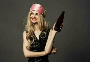 schön blond mit ein Rosa Schlaf Maske und ein Flasche von Bier im ihr Hand foto