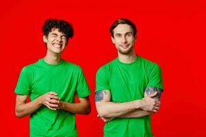 zwei Männer im Grün T-Shirts sind Stehen Seite durch Seite Kommunikation Emotionen Freundschaft foto