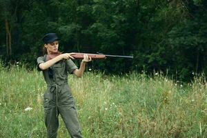 Frau Grün Overall Waffe im das Hände von Jagd frisch Luft frisch Luft foto