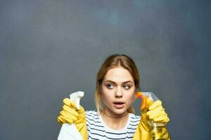 Reinigung Dame im gestreift T-Shirt Gummi Handschuhe abgeschnitten grau Hintergrund foto