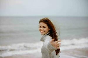 Frau rot Haar im ein Sweatshirt durch das Ozean unverändert foto