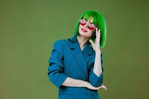 Frau im Grün Perücke stilvoll Brille Mode posieren Grün Hintergrund foto