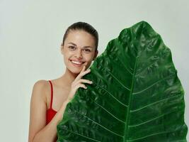 lächelnd Frau im rot Badeanzug Palme Blatt exotisch Licht Hintergrund foto