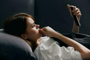 Porträt von ziemlich Frau mit Handy, Mobiltelefon Telefon auf Sofa foto