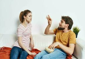 Mann und Frau auf das Couch drinnen chatten freunde Popcorn foto