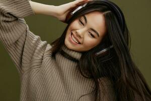 Brünette im ein Sweatshirt Hören zu Musik- mit Kopfhörer Spaß isoliert Hintergrund foto