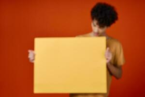 Kerl mit lockig Haar Gelb Poster im Hände Studio Werbung foto