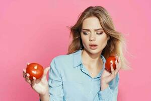 Frau im Blau Hemd halten Tomaten Spaß Essen Rosa Hintergrund foto