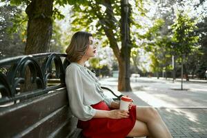 Frau im rot Rock im das Park auf das Bank draußen foto