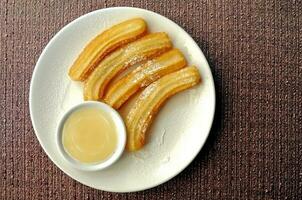 frisch gemacht Spanisch Churros mit Weiß Schokolade Eintauchen Saft foto