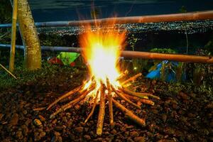 Lagerfeuer und etwas Funken auf das Camping Boden, mit Stadtlicht im das Hintergrund foto