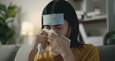 jung asiatisch Frau Leiden von Grippe mit ein fiebersenkend Patch auf ihr Stirn foto