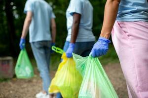 glücklich Freiwillige verbinden nach Reinigung oben das Umgebung im ein Öffentlichkeit Park, gehen einer nach das andere und gehen zu Ein weiterer Standort. selektiv Fokus foto