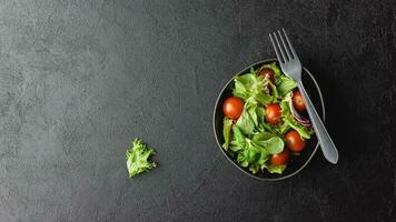 grüne salatblätter in schüssel auf schwarzem tisch. foto