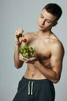 sportlich Mann mit gepumpt oben Abs gesund Essen Essen Gemüse Salat Fitness foto