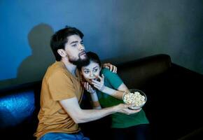 freunde Mann und Frau Aufpassen Fernseher auf das Couch und Popcorn im ein Teller foto