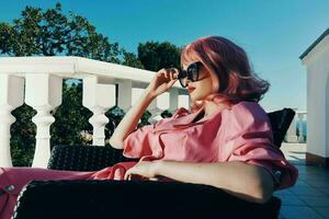 attraktiv Frau Rosa Kleid sitzt auf das Terrasse Entspannung Konzept foto