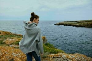 Porträt von ein Frau Pullover wolkig Meer bewundern Natur Lebensstil foto