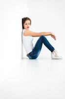 fröhliches Mädchen in einem weißen T-Shirt und dunkelblauen Jeans im Studio auf einem weißen Hintergrund foto