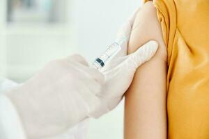 ein Arzt spritzt ein covid-19 Impfstoff in ein Frau Schulter foto