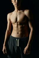 männlich Bodybuilder im grau Hose nackt Torso gepumpt oben Muskeln schwarz Hintergrund foto