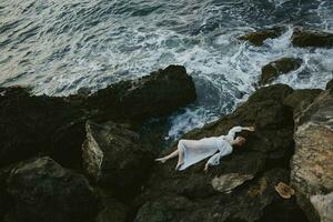 Frau im ein Weiß Kleid Lügen auf ein Stein im ein Weiß Kleid Landschaft foto