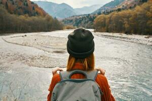 Frau im ein Sweatshirt und Deckel mit ein Rucksack auf ihr zurück im das Berge auf Natur Landschaft foto