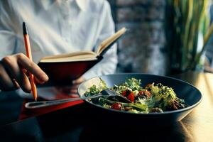 Notizblock mit ein Stift im Hand und Salat im ein Teller Restaurant Cafe Inschrift foto