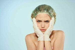 Frau mit nackt Schultern halten ihr Gesicht im Handschuhe Haut Pflege Dermatologie foto