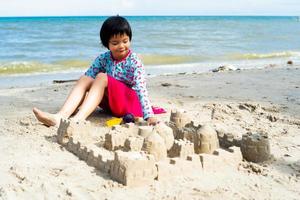 Porträt eines Asain-Mädchens, das im Sand mit Spielzeug spielt und eine Sandburg baut. foto