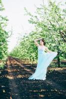 brünettes Mädchen in einem türkisfarbenen Kleid im Frühlingsgarten foto