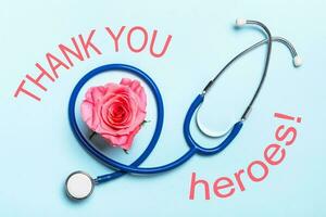 danken Sie zu Gesundheitswesen Helden covid-19 Pandemie Poster. schön Herz Rose und Stethoskop auf Blau Hintergrund foto