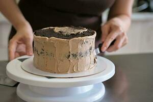 Frau Gebäck Koch Herstellung Schokolade Kuchen mit Schokolade Creme, Nahansicht. Kuchen Herstellung Verfahren, selektiv Fokus foto