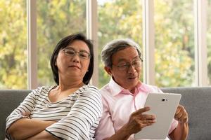 Senior asiatischer Mann und Frau entspannen im Urlaub im natürlichen Wohnzimmerhintergrund mit moderner Technologie